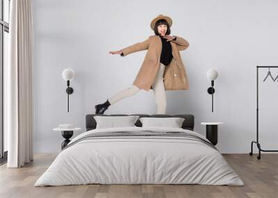 Young pretty girl jumping in beige coat isolated on white background Wall mural